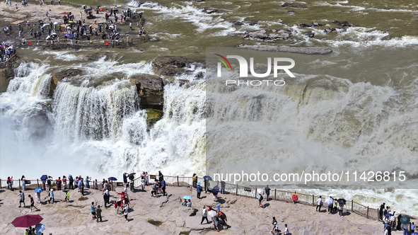 Tourists are visiting Hukou Waterfall on the Yellow River at the junction of Yichuan county and Ji county in North China's Shaanxi province,...