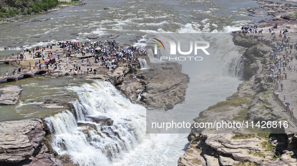 Tourists are visiting Hukou Waterfall on the Yellow River at the junction of Yichuan county and Ji county in North China's Shaanxi province,...