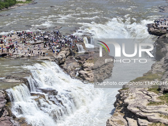 Tourists are visiting Hukou Waterfall on the Yellow River at the junction of Yichuan county and Ji county in North China's Shaanxi province,...