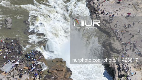 Tourists are visiting Hukou Waterfall on the Yellow River at the junction of Yichuan county and Ji county in North China's Shaanxi province,...