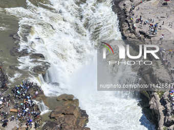 Tourists are visiting Hukou Waterfall on the Yellow River at the junction of Yichuan county and Ji county in North China's Shaanxi province,...