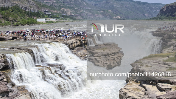 Tourists are visiting Hukou Waterfall on the Yellow River at the junction of Yichuan county and Ji county in North China's Shaanxi province,...