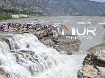 Tourists are visiting Hukou Waterfall on the Yellow River at the junction of Yichuan county and Ji county in North China's Shaanxi province,...