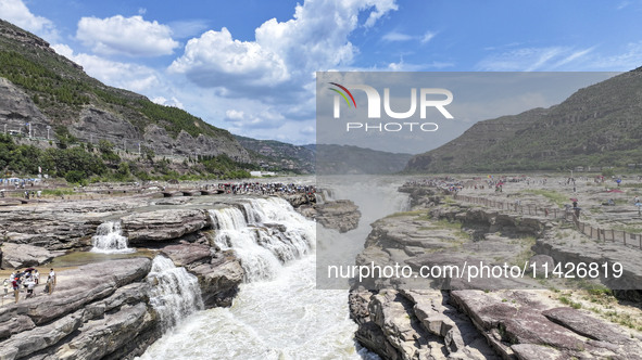 Tourists are visiting Hukou Waterfall on the Yellow River at the junction of Yichuan county and Ji county in North China's Shaanxi province,...