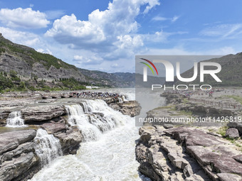 Tourists are visiting Hukou Waterfall on the Yellow River at the junction of Yichuan county and Ji county in North China's Shaanxi province,...