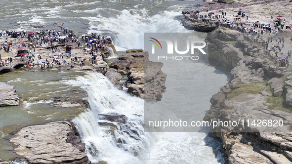 Tourists are visiting Hukou Waterfall on the Yellow River at the junction of Yichuan county and Ji county in North China's Shaanxi province,...