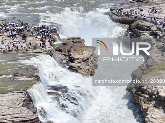 Tourists are visiting Hukou Waterfall on the Yellow River at the junction of Yichuan county and Ji county in North China's Shaanxi province,...