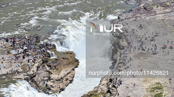 Tourists are visiting Hukou Waterfall on the Yellow River at the junction of Yichuan county and Ji county in North China's Shaanxi province,...