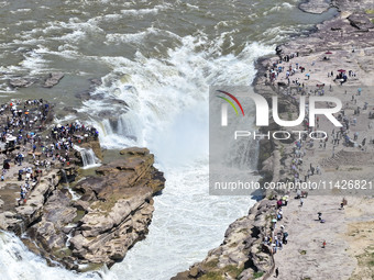 Tourists are visiting Hukou Waterfall on the Yellow River at the junction of Yichuan county and Ji county in North China's Shaanxi province,...