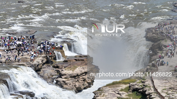 Tourists are visiting Hukou Waterfall on the Yellow River at the junction of Yichuan county and Ji county in North China's Shaanxi province,...