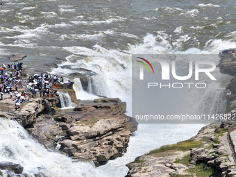 Tourists are visiting Hukou Waterfall on the Yellow River at the junction of Yichuan county and Ji county in North China's Shaanxi province,...