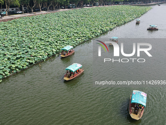 Tourists are taking a boat ride to see lotus flowers blooming on the West Lake in Hangzhou, China, on July 22, 2024. (