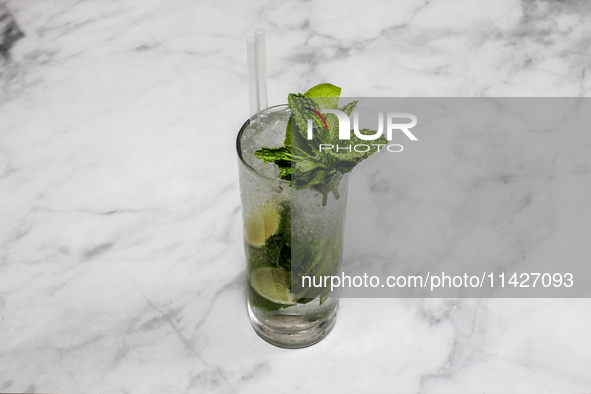 A cocktail ''Mojito'' is sitting on a bright background. 