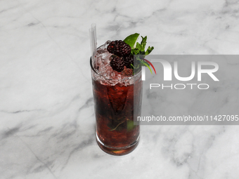 A cocktail ''Blackberry Mojito'' is sitting on a bright background. (