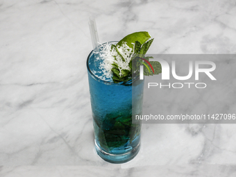 A cocktail ''Blue Hawaiian Mojito'' is sitting on a bright background. (