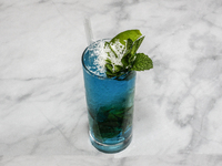 A cocktail ''Blue Hawaiian Mojito'' is sitting on a bright background. (