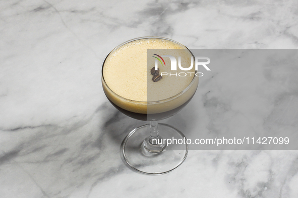 A cocktail ''Espresso Martini'' is sitting on a bright background. 