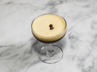 A cocktail ''Espresso Martini'' is sitting on a bright background. (