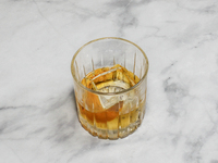 A cocktail ''Old Fashioned'' is sitting on a bright background. (