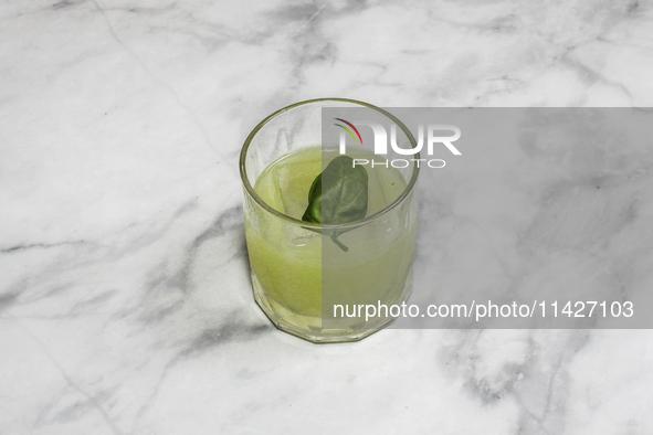 A cocktail ''Gin Basil Smash'' is sitting on a bright background. 