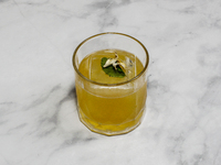 The cocktail ''Penicillin'' is sitting on a bright background. (