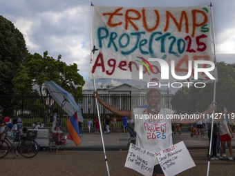 An activist is showing a sign with the words "Trump's Project 2025 Agenda 47" among other informative texts in front of the White House in W...