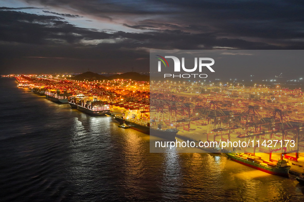 A photo is showing the working scene at the wharf of Shanghai Yangshan Port in Shanghai, China, on July 21, 2024, in the evening. 