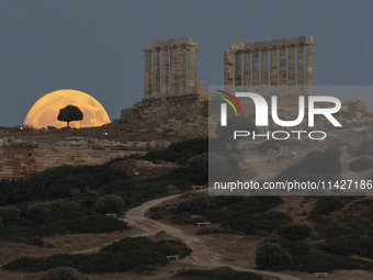 The Full Buck Moon rises behind the ancient Greek Temple of Poseidon on Cape Sounion in Greece on July 20, 2024 (