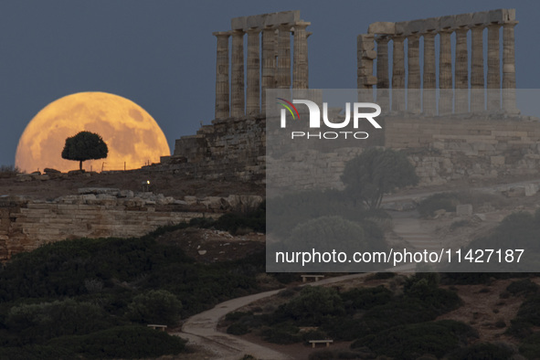 The Full Buck Moon rises behind the ancient Greek Temple of Poseidon on Cape Sounion in Greece on July 20, 2024 