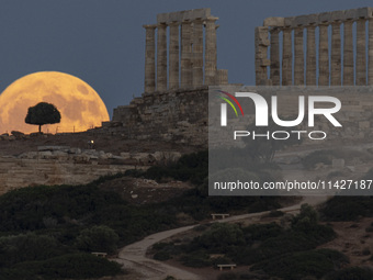 The Full Buck Moon rises behind the ancient Greek Temple of Poseidon on Cape Sounion in Greece on July 20, 2024 (