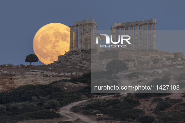 The Full Buck Moon rises behind the ancient Greek Temple of Poseidon on Cape Sounion in Greece on July 20, 2024 