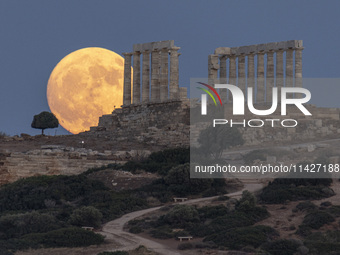 The Full Buck Moon rises behind the ancient Greek Temple of Poseidon on Cape Sounion in Greece on July 20, 2024 (