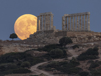 The Full Buck Moon rises behind the ancient Greek Temple of Poseidon on Cape Sounion in Greece on July 20, 2024 (