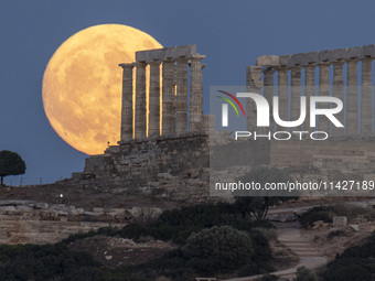 The Full Buck Moon rises behind the ancient Greek Temple of Poseidon on Cape Sounion in Greece on July 20, 2024 (