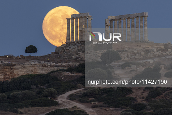 The Full Buck Moon rises behind the ancient Greek Temple of Poseidon on Cape Sounion in Greece on July 20, 2024 