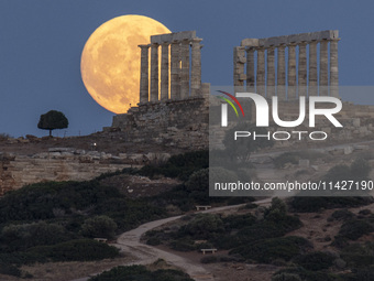 The Full Buck Moon rises behind the ancient Greek Temple of Poseidon on Cape Sounion in Greece on July 20, 2024 (