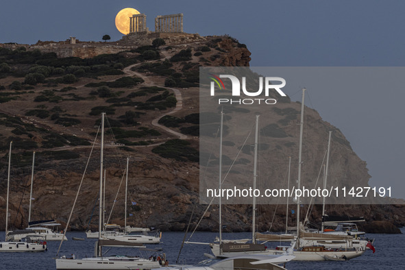 The Full Buck Moon rises behind the ancient Greek Temple of Poseidon on Cape Sounion in Greece on July 20, 2024 