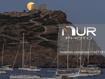 The Full Buck Moon rises behind the ancient Greek Temple of Poseidon on Cape Sounion in Greece on July 20, 2024 (