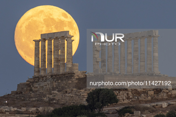 The Full Buck Moon rises behind the ancient Greek Temple of Poseidon on Cape Sounion in Greece on July 20, 2024 