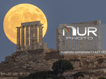 The Full Buck Moon rises behind the ancient Greek Temple of Poseidon on Cape Sounion in Greece on July 20, 2024 (