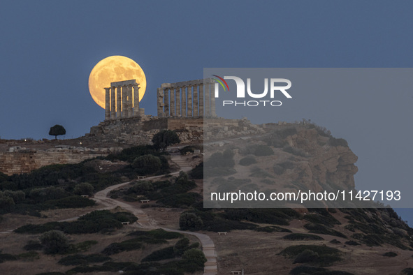 The Full Buck Moon rises behind the ancient Greek Temple of Poseidon on Cape Sounion in Greece on July 20, 2024 