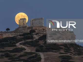 The Full Buck Moon rises behind the ancient Greek Temple of Poseidon on Cape Sounion in Greece on July 20, 2024 (