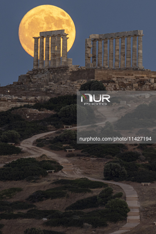 The Full Buck Moon rises behind the ancient Greek Temple of Poseidon on Cape Sounion in Greece on July 20, 2024 