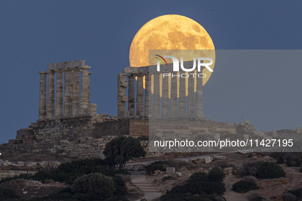 The Full Buck Moon rises behind the ancient Greek Temple of Poseidon on Cape Sounion in Greece on July 20, 2024 