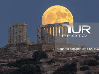 The Full Buck Moon rises behind the ancient Greek Temple of Poseidon on Cape Sounion in Greece on July 20, 2024 (