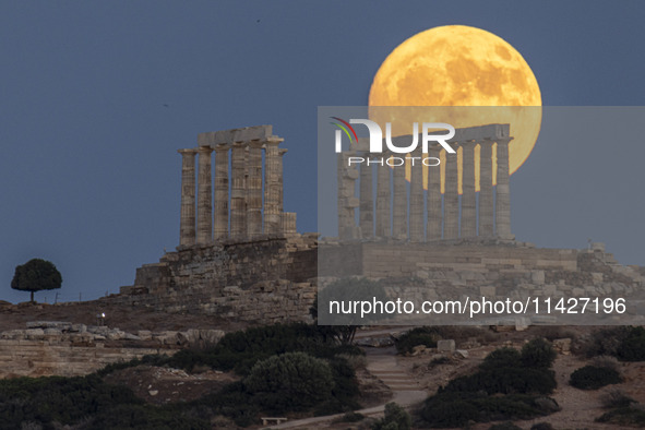 The Full Buck Moon rises behind the ancient Greek Temple of Poseidon on Cape Sounion in Greece on July 20, 2024 