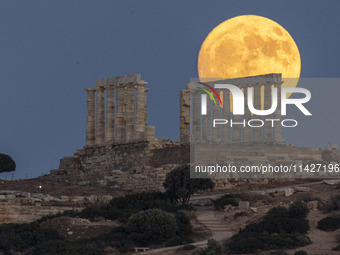 The Full Buck Moon rises behind the ancient Greek Temple of Poseidon on Cape Sounion in Greece on July 20, 2024 (