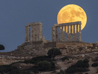 The Full Buck Moon rises behind the ancient Greek Temple of Poseidon on Cape Sounion in Greece on July 20, 2024 (