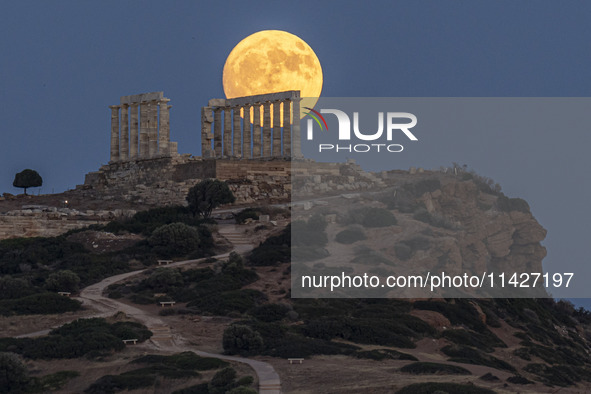 The Full Buck Moon rises behind the ancient Greek Temple of Poseidon on Cape Sounion in Greece on July 20, 2024 