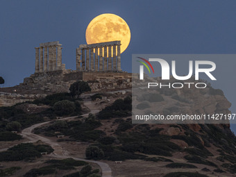 The Full Buck Moon rises behind the ancient Greek Temple of Poseidon on Cape Sounion in Greece on July 20, 2024 (